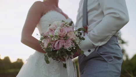 Bride-and-Groom-holding-beautiful-Bridal-Bouquet-Flowers-at-Sunset