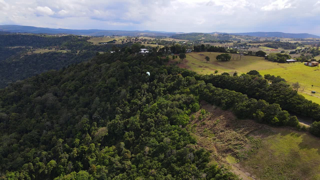 Parapendista in volo sopra montagne verdi al Rosins Lookout Conservation Park in estate - Rosin's Lookout - Beechmont, QLD, Australia