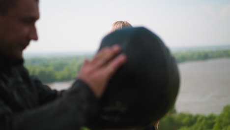 Woman-enjoys-view-of-picturesque-river-man-takes-off-hardhat