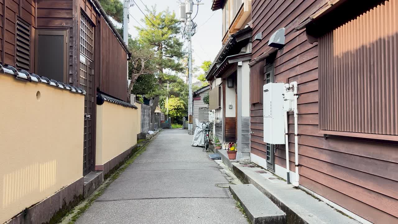 A slow forward tracking shot through a quiet narrow street with traditional Japanese wooden houses