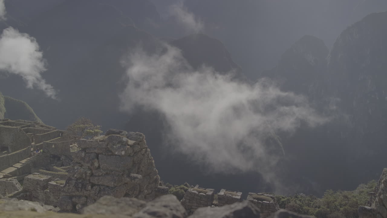 Low hanging cloud above the ruins of Machu Picchu Peru on a sunny day LOG