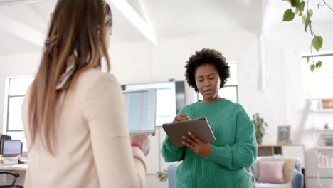 Diverse-business-female-colleagues-in-discussion-using-tablet-in-casual-office-meeting,-slow-motion