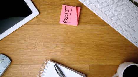 pink sticky notes with profit written in bold falling on office desk