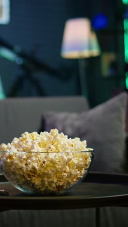 vertical video bowl of popcorn on table in empty neon lit cozy residential interior