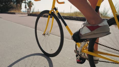 person cycling on a yellow fixed gear bicycle on a coastline path