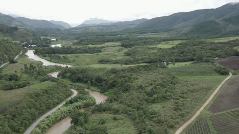 Aerial-tilt-to-winding-Huancabamba-River-in-cloudy-green-valley,-Peru