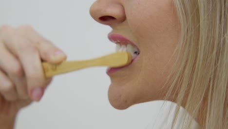 una mujer de piel clara cepillando los dientes, de cerca