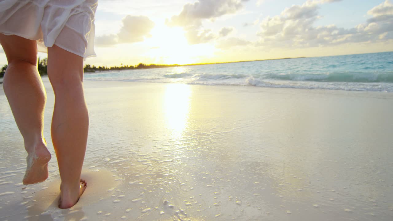 joven mujer caucásica caminando descalza por la playa