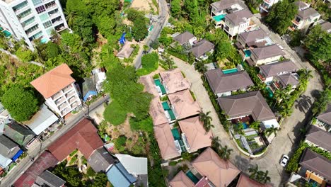 Drone footage captures lush greenery and villa rooftops in a Phuket resort. Bright daylight enhances the vibrant tropical setting