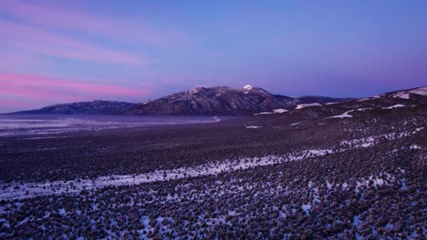 pink and purple sunset or sunrise over a mountain peak in the winter