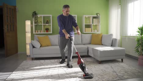 mature man vacuuming house in apartment.