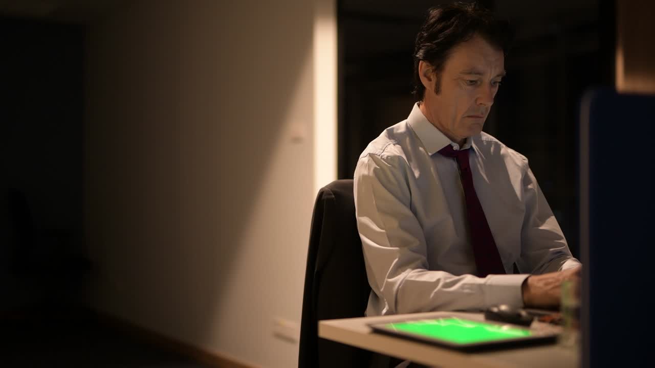 Mature Businessman Sitting And Working In Office At Night