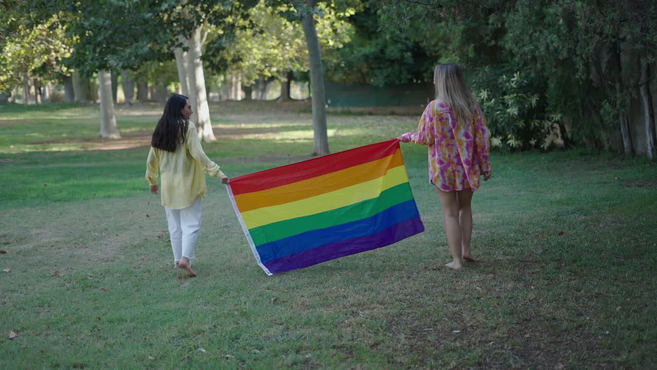 Two Women Holding a Pride Flag in a Park