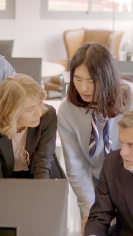 Business partners looking at the same computer in a coworking
