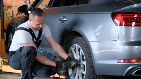 mechanic changing a tire on a grey car at an auto service station