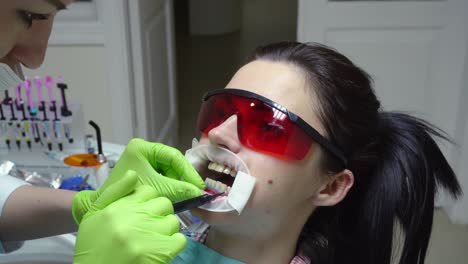 young woman with an expander in mouth at the dental clinic. application of protective whitening gel to the teeth. modern dental office. shot in 4k