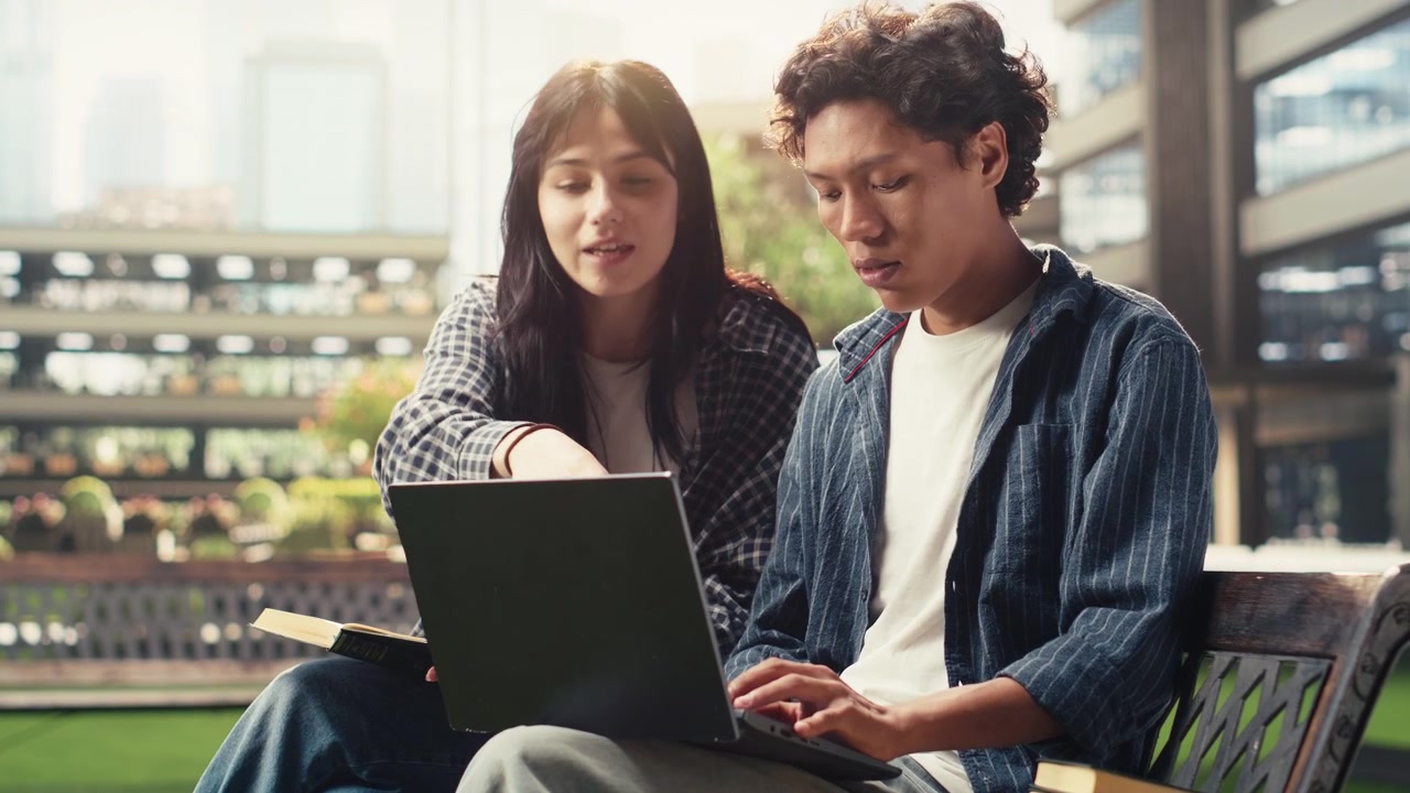 Studerende gennemgår laptop-projekt sammen på campusbænk