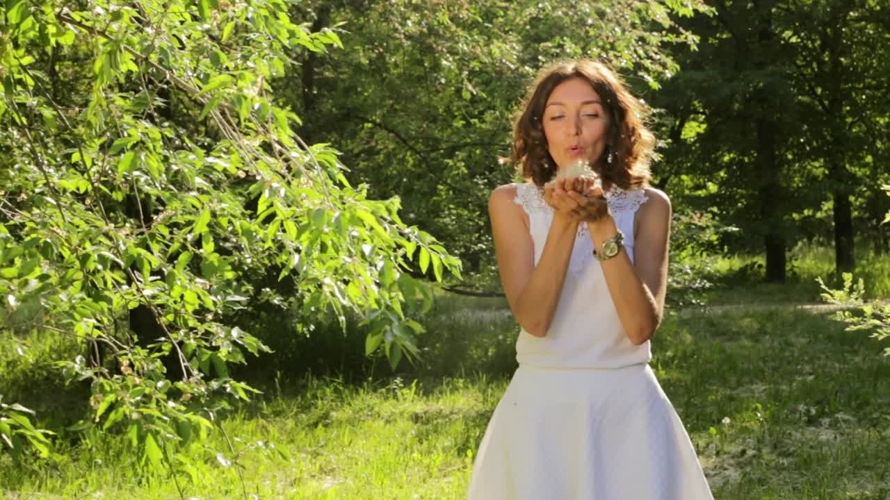 Woman Blowing Dandelion Seeds in a Park