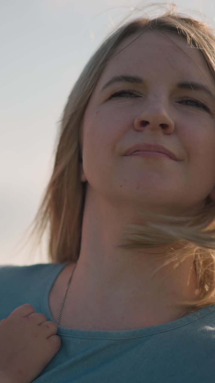 primer plano de una mujer con un vestido azul llevando a su hijo pequeño, que lleva una camiseta blanca. el niño parece triste mientras la mujer mueve suavemente el cabello de su cara