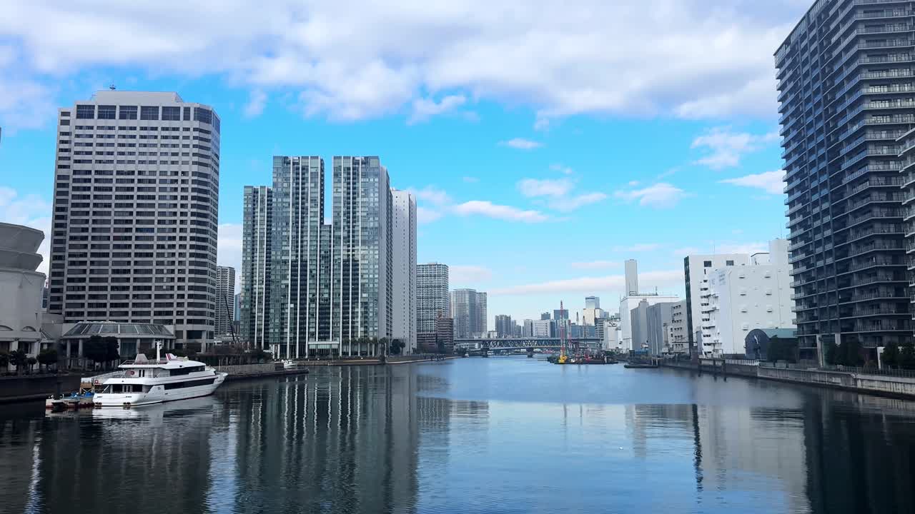 A peaceful canal scene in modern Tokyo with tall buildings and a yacht moored nearby