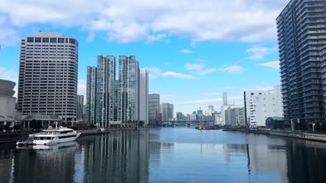 a peaceful canal scene in modern tokyo with tall buildings and a yacht moored nearby