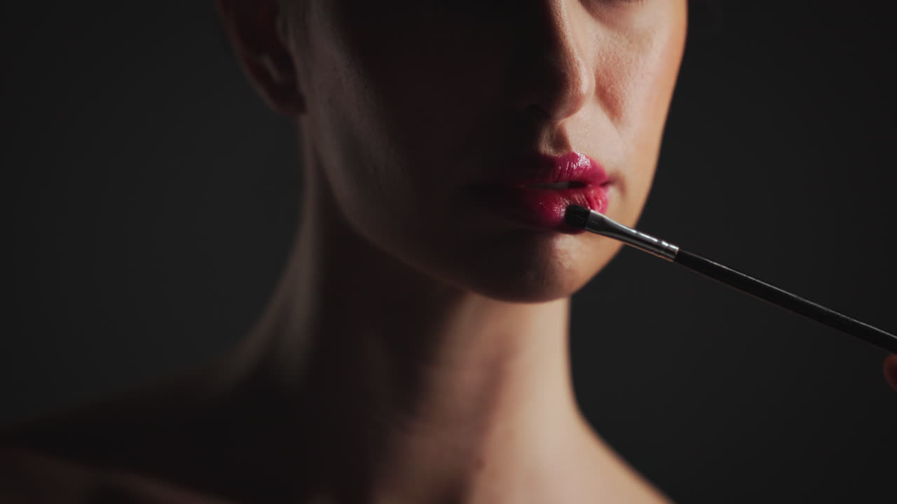 Woman applying lipstick with a brush