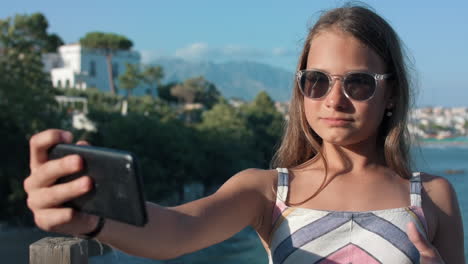una chica sonriente enviando un beso aéreo por teléfono celular. una mujer feliz haciendo muecas al aire libre.