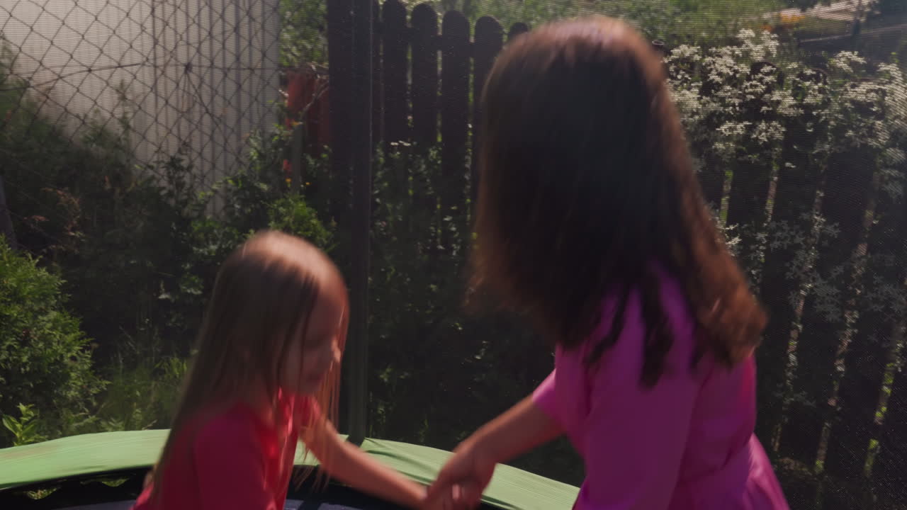 Woman Holding ChildS Hands On Trampoline To Help Balance, Tender Guiding Motion In Shaded Backyard, Steady Supportive Interaction With Safety Net And Green Lawn, Calm Family Moment