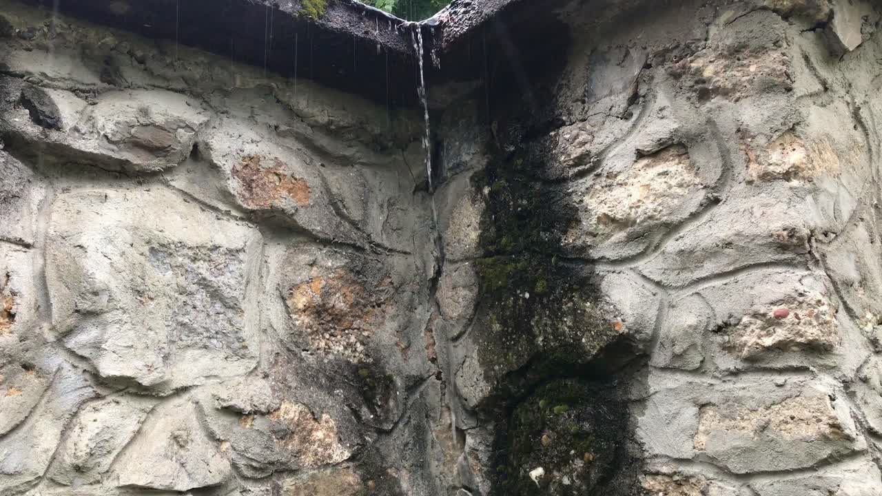 Pouring rain on old stone wall