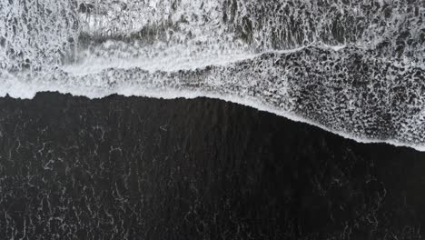 Drohnenaufnahme-Von-Oben-Nach-Unten,-Wellen-Rauschen-An-Der-Küste-Des-Schwarzen-Sandstrandes-Hoch