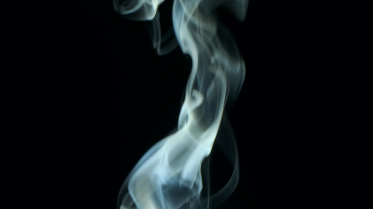 Sottile rivolo di fumo argenteo che sale lentamente con eleganti volute verso l'alto. Fumo di sigaro che si muove dal basso verso l'alto. Primo piano, isolato su sfondo nero