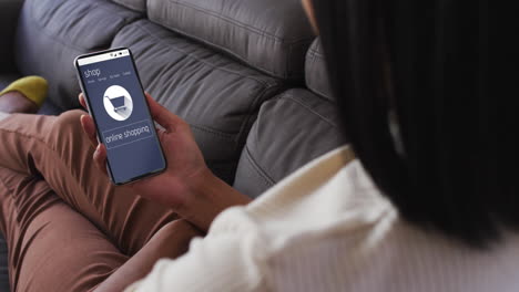 Biracial-woman-on-couch-using-smartphone-for-online-shopping,-slow-motion