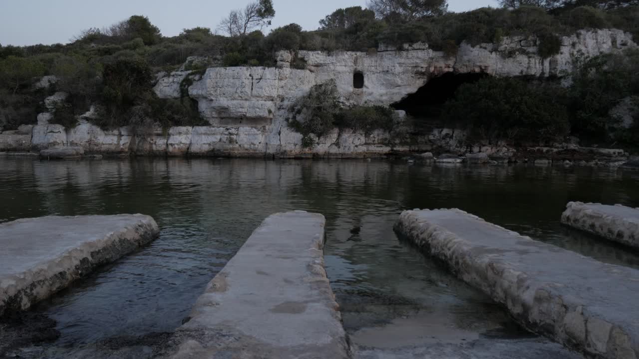 Rocky coastline at Cala Alcaufar with stone platforms leading into the water