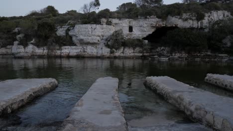 rocky coastline at cala alcaufar with stone platforms leading into the water