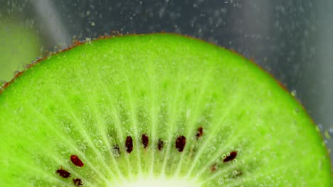 a piece of green kiwi under water with air bubbles.