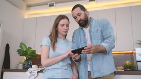 bearded man showing mobile phone photos to an attractive woman 1