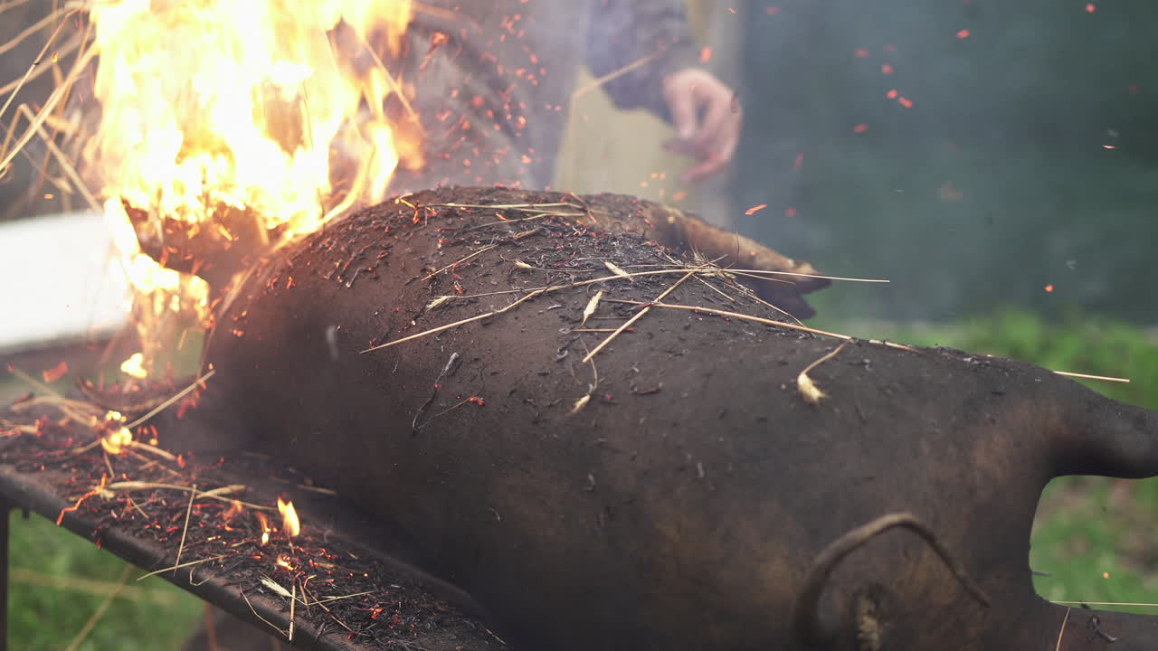 불타는 짚 묶음으로 돼지 시체에서 머리카락을 제거하는 남자 - 클로즈업