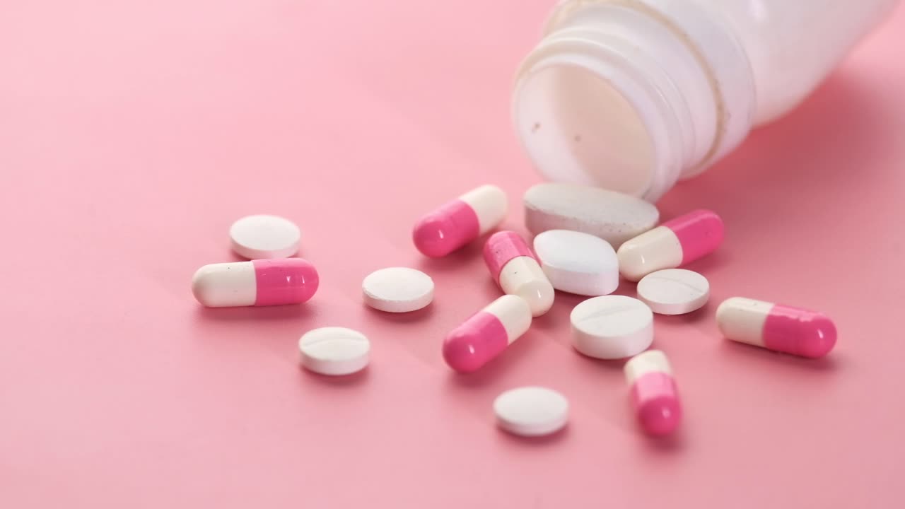Pink Background with Assorted Pills and Medicine Bottle