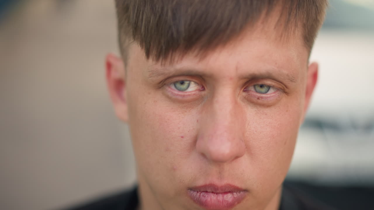 caucasian man closeup intense stare into camera, outdoor shallow depth with soft bokeh, confident attitude, clean haircut and strong jawline, mood cinematic and tactile skin detail