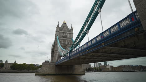 wide angle of boats driving under the tower bridge in london on the river thames on a cloudy day