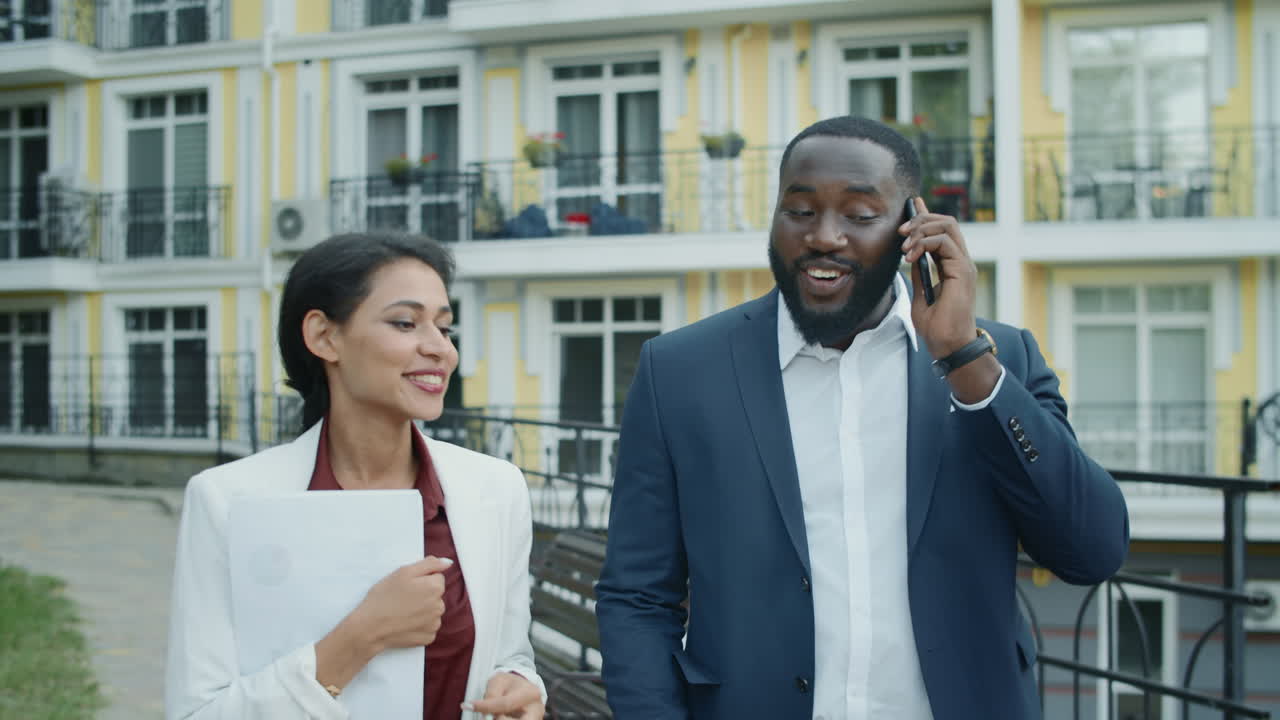 Couple d'affaires passant un appel téléphonique à l'extérieur. Homme et femme marchant en plein air.