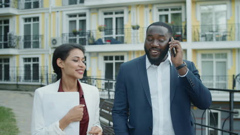 business couple having phone call outside. man and woman walking outdoors