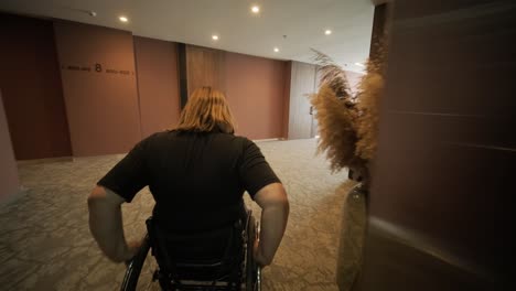 a woman in a wheelchair is inside an elevator, holding an item in her hands, as she waits for the elevator to reach her floor. the image highlights accessibility, independence, and modern infrastructure.