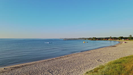 flying over the blue calm water by the shore on a sunny day in sandbybadet, öland, sweden