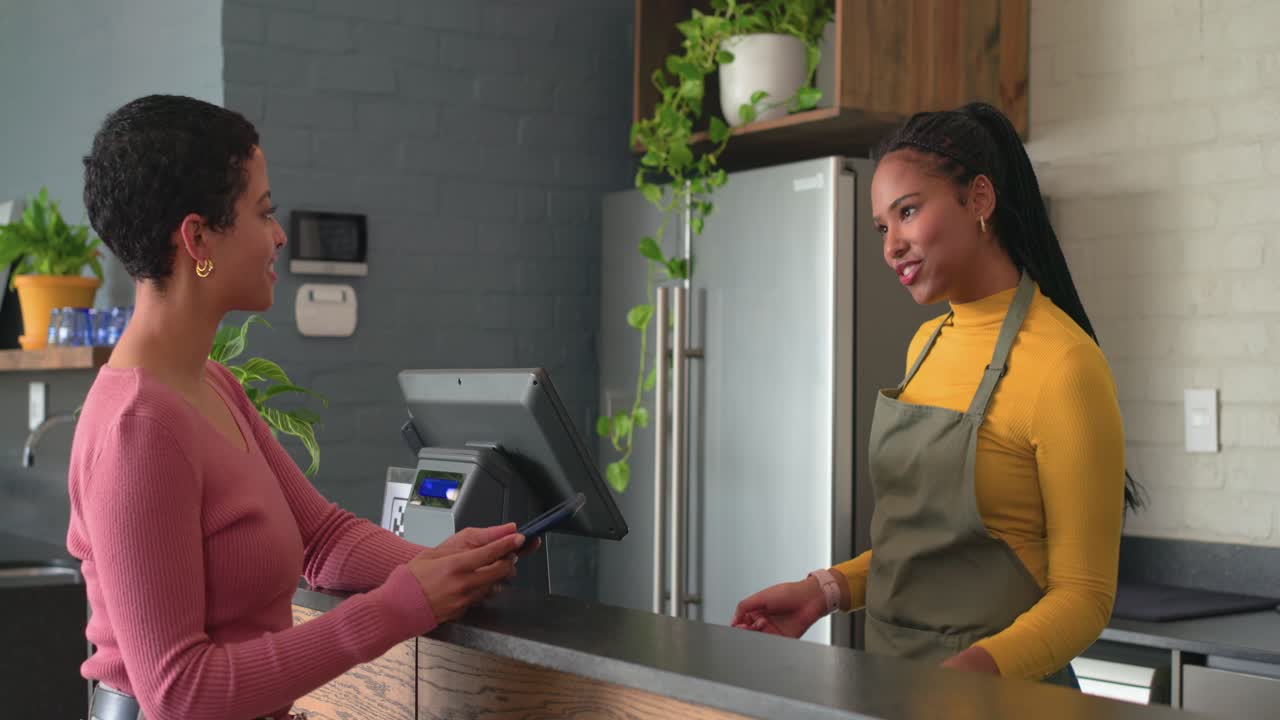 Barista e cliente acertando o pagamento após consulta ao menu e leitura do celular no café, espaço para texto