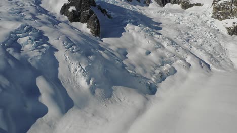 4K-drone-shot-looking-down-at-glacier-and-panning-up-to-reveal-huge-mountain-summit