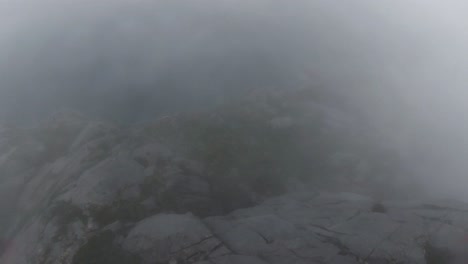 cliffdiving una montaña en noruega comenzando en la niebla, a medida que la niebla se despeja se puede ver un lago en el valle y un pájaro pasa volando