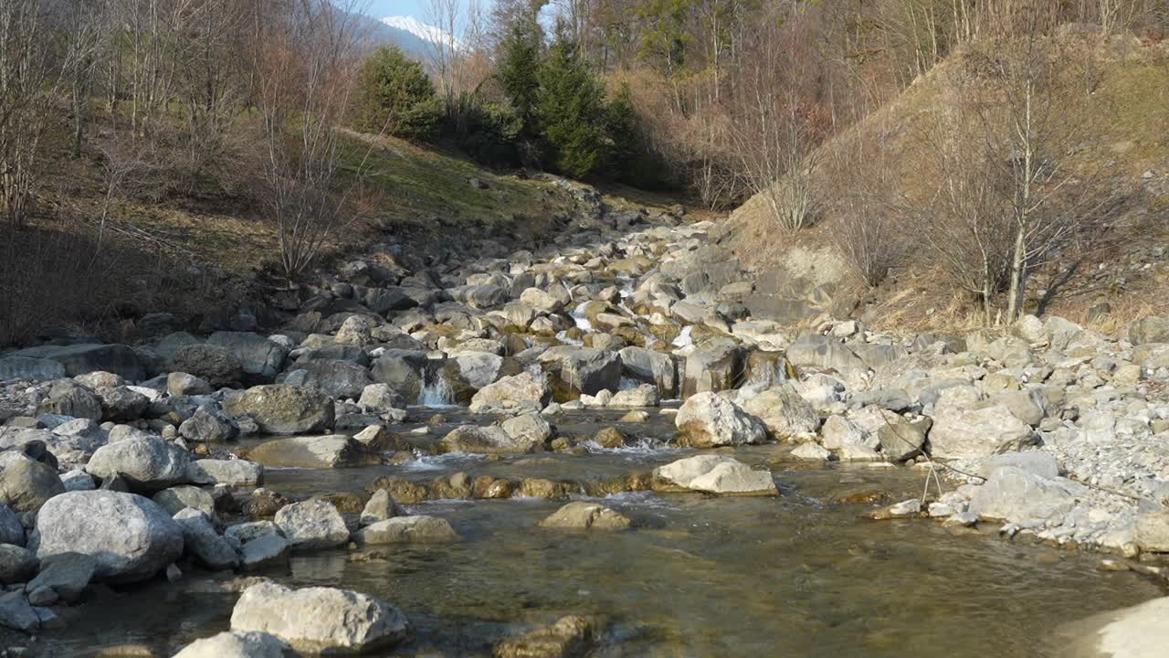 Slow-motion shot of a mountain river of stones flowing into the serene Walensee lake in Switzerland.