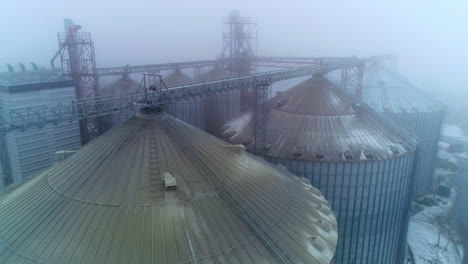 the rounded tops of the silo tanks. drone shot over the modern grain elevators on foggy weather. impressive granary constructions from aerial perspective.
