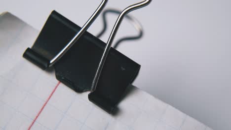 person fixes clamp on notebook paper in white background